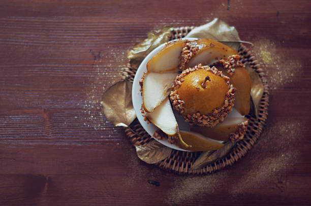 istock Caramelized pear dipped with peanuts decorated with golden leaves 487565620