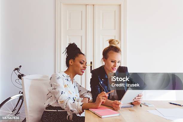 Two Women Working On Digital Tablet In An Office Stock Photo - Download Image Now - Social Media, Manager, Small Business
