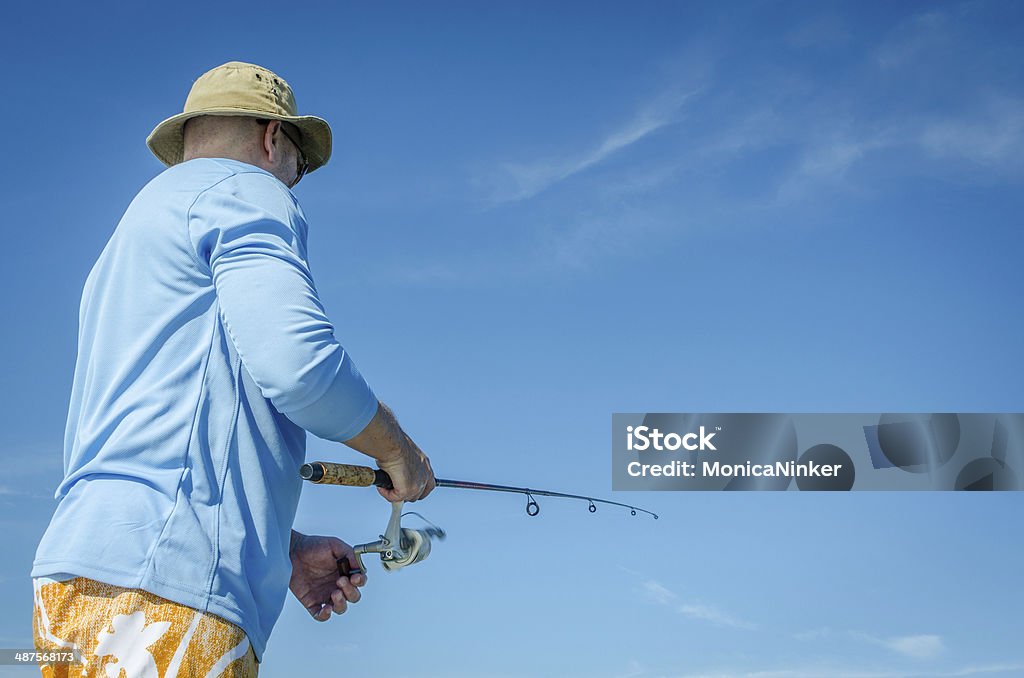 Man with hat fishing Mature man fishing in the ocean Fishing Stock Photo