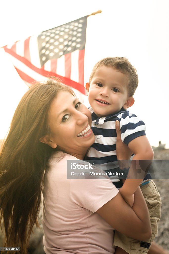 Happy mother and son Happy immigrant mother holding her little boy with the american flag on the background American Flag Stock Photo