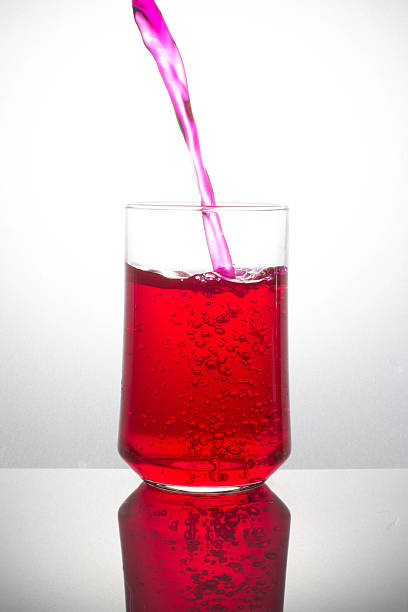 istock pouring red drink splash into glass on white background 487568730