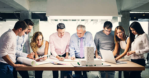 Team of architects reviewing architectural model in the office.