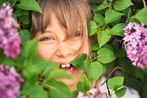 Little girl having fun hiding inside lilac.