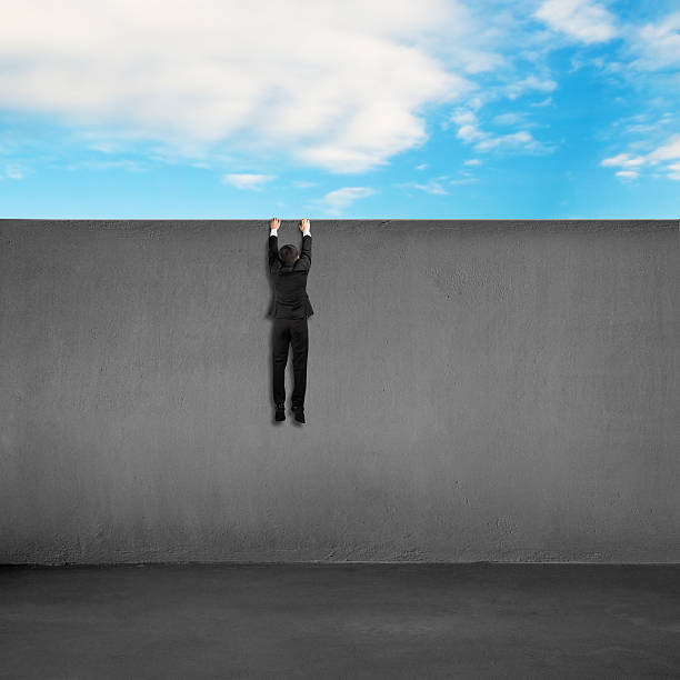 istock Trying to climb over wall with blue sky background 487574903