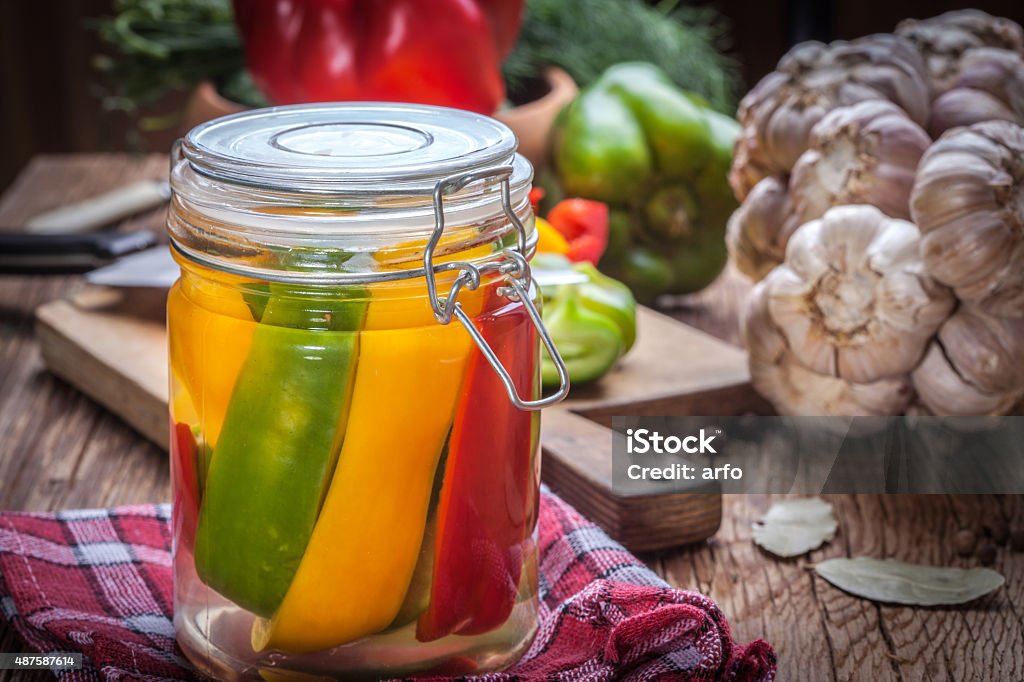 Pickled peppers. Multi-colored homemade pickled peppers on a wooden table. 2015 Stock Photo