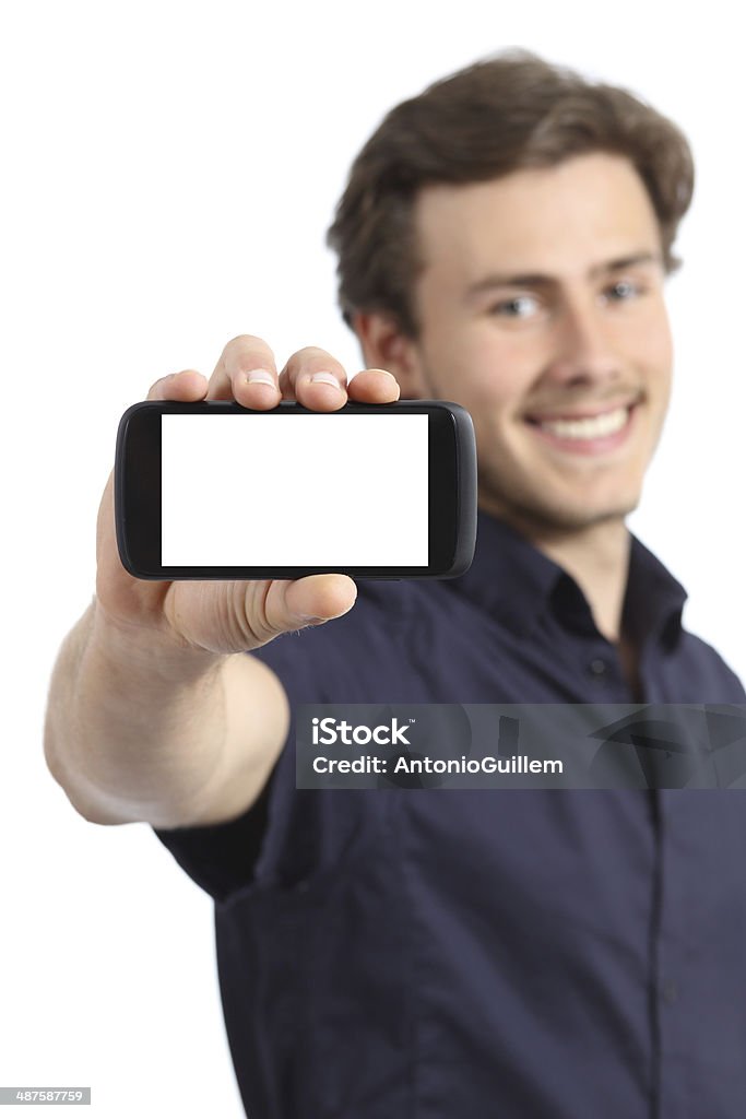 Handsome young man showing a blank smart phone display Handsome young man showing a blank smart phone display isolated on a white background Boys Stock Photo