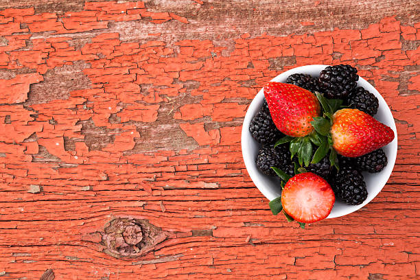 Handful of strawberries and blackberries on a wooden surface
