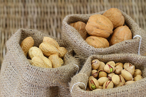 noix de grenoble, pistache et noix et cacahuètes dans des sacs de toile de jute - nobody food canvas peanut photos et images de collection