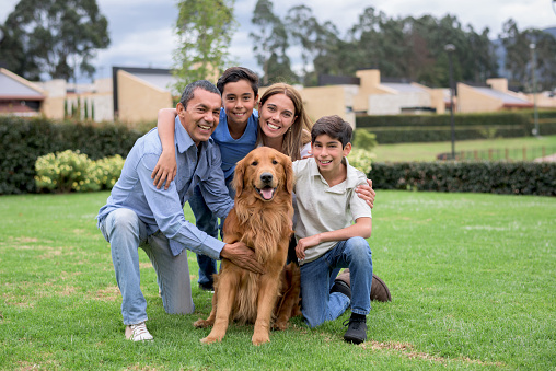 Happy Latin American family with a dog at home playing in the backyard and looking at the camera smiling