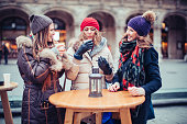 Friends having hot drinks outdoors in winter city.