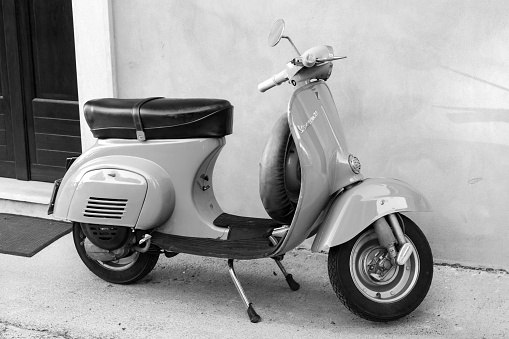 Gaeta, Italy - August 19, 2015: Classic yellow Vespa scooter stands parked near the wall