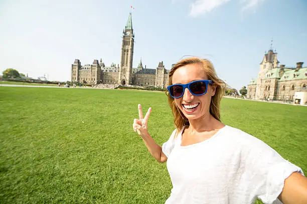 Photo of tourist in Ottawa taking selfie with parliament building