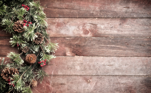 A festive and rustic Christmas pine wreath hanging on old wood door