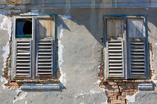 old wooden window with open shutter and roll up jalousie, bright cement wall with rough surface, no people