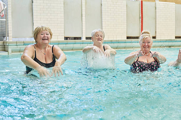 istock senior ladies splashing in pool 487605234