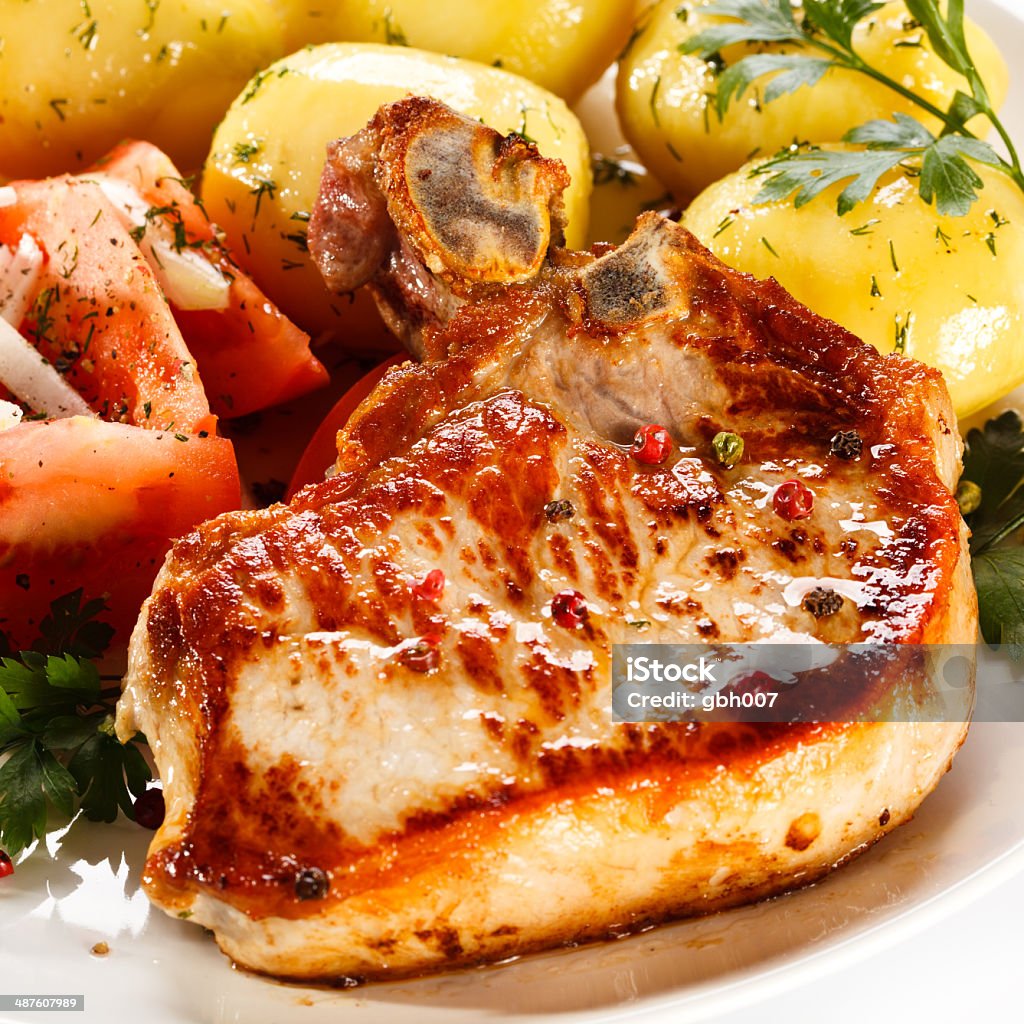 Pork chop, boiled potatoes and vegetables on white background Fried pork chop with vegetables  Boiled Potato Stock Photo