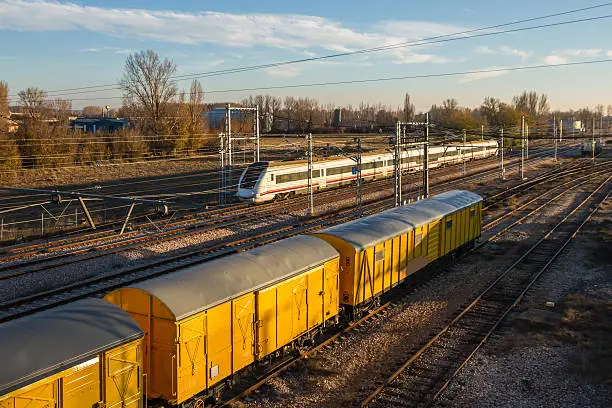 Moving train and train cars freshly painted yellow on the tracks with sunset light