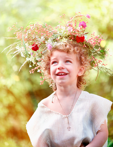 Child Wearing a Flower Wreath and Smiling