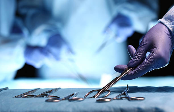Surgery and emergency concept Nurse hand taking surgical instrument for group of surgeons at background operating patient in surgical theatre. Steel medical instruments ready to be used. Surgery and emergency concept scalpel photos stock pictures, royalty-free photos & images