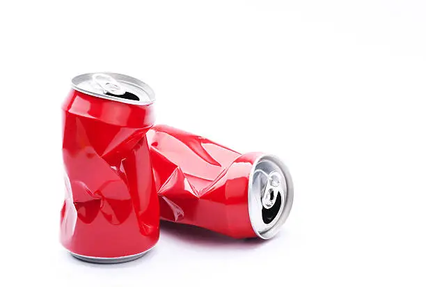 Red crushed cans on white background, recycling and pollution concept.