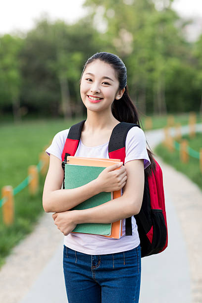 istock female student outdoors holding a notebook and smiling 487636350