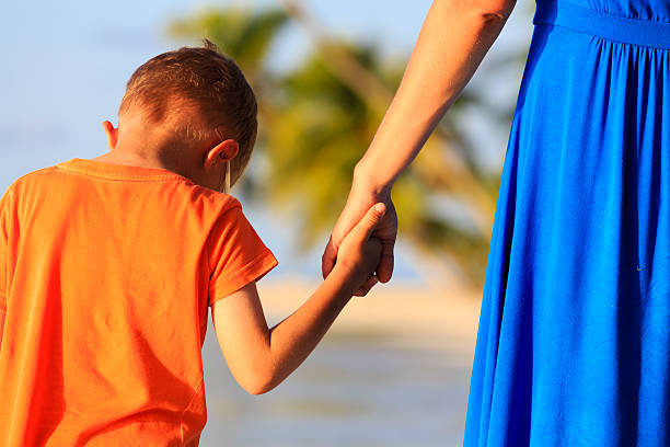 istock mother and son holding hands on beach 487646856
