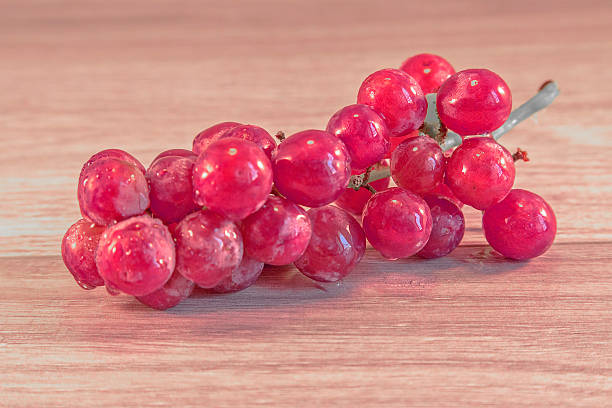grapes Grapes lying on a wooden surface, with a spider crawing accross them animall stock pictures, royalty-free photos & images