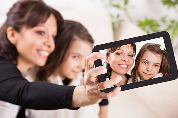 istock Mother and daughter taking self portraits with tablet 487648681