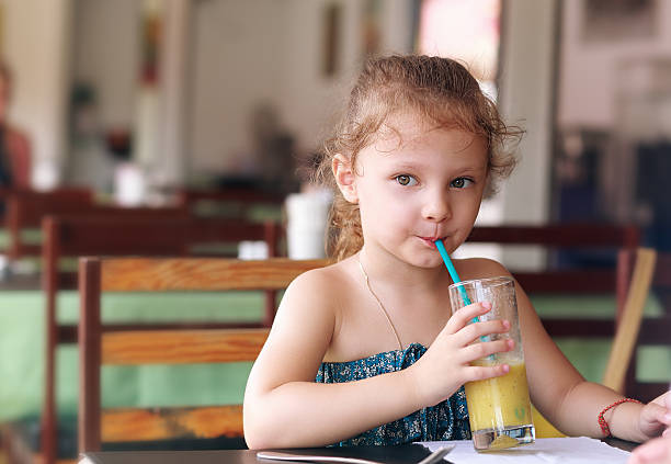 istock Cute small kid girl drinking juice in cafe 487654254