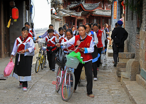 Lijiang, China - June 10, 2015: big group of women clothed in the same clothes is moving on the street in Lijiang, China