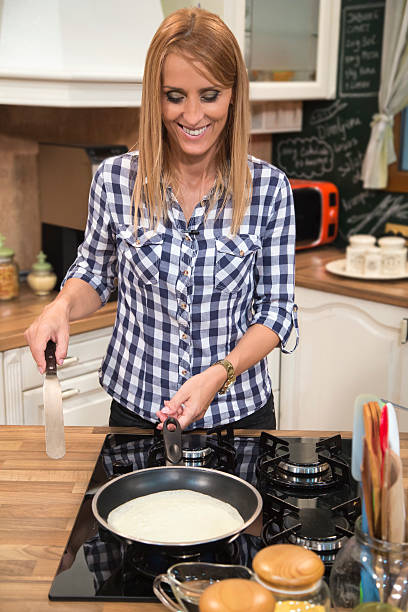 istock Smiling woman making gluten free pancakes in kitchen. 487655550