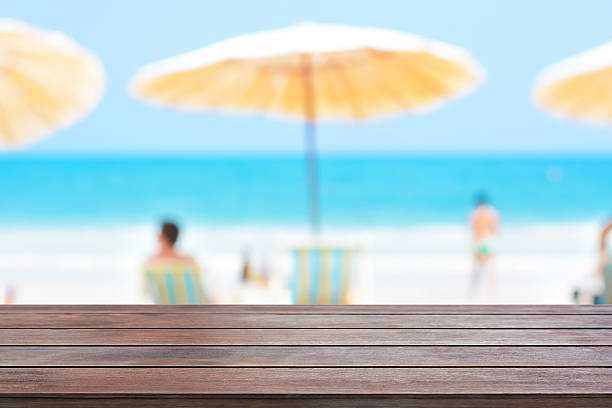 istock Old dark brown wood table top on blurred beach background 487658082