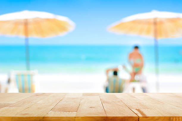 istock Wood table top on blurred beautiful white sand beach background 487658108