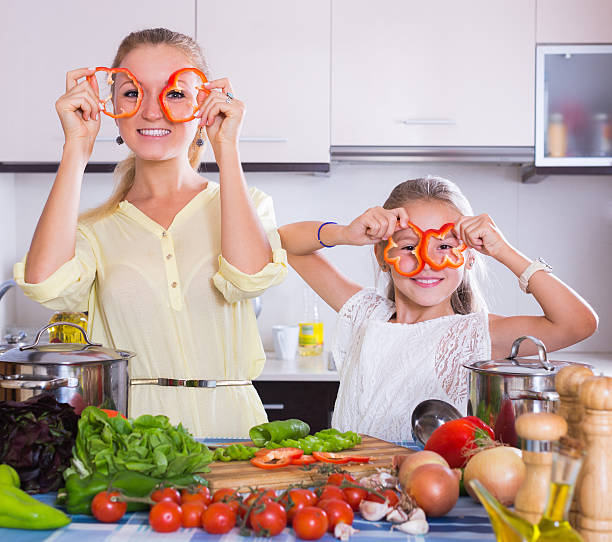 istock Mother with daughter cooking veggies 487665370
