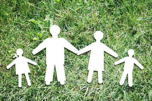 Happy parents with children on backdrop of green grass. Abstract conceptual image