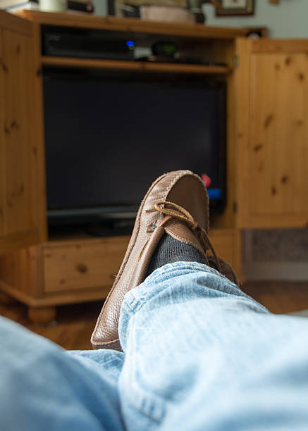 istock Man's feet with slippers with television in the background 487668558