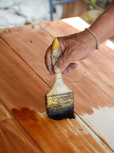 istock carpenter s hands paintbrush varnish to wood table 487671097