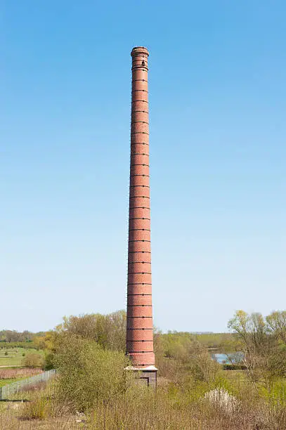 Stone chimney of an ancient Dutch brick factory in river landscape