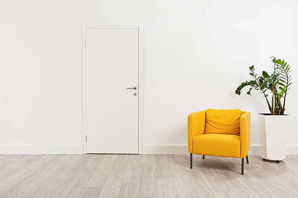 Contemporary waiting room with a yellow armchair Contemporary waiting room with a yellow armchair and a plant in a white flowerpot behind it armchair photos stock pictures, royalty-free photos & images