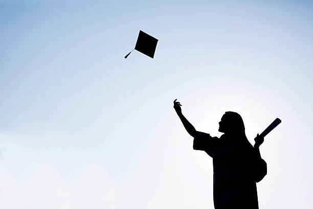 istock Graduate students tossing up hats over blue sky 487672220