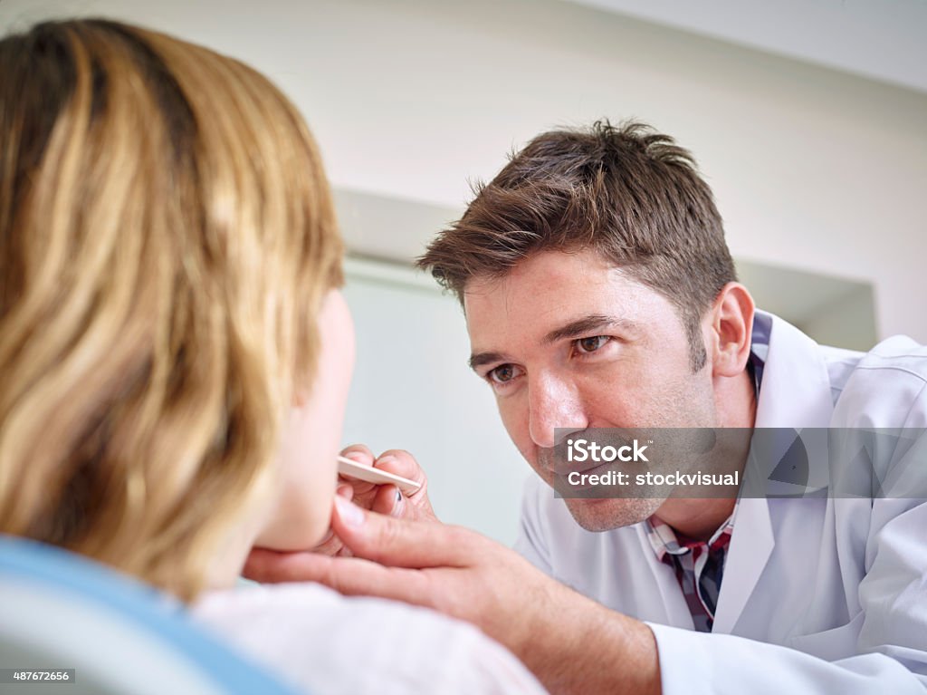 Doctor examining a woman's throat 2015 Stock Photo