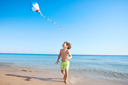 Boy running on the beach with a kite