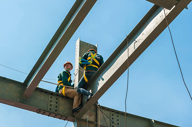 Builder workers in safety protective assemble metal construction frame Ho Chi Minh City, Vietnam - September 18, 2014: Builder workers in safety protective equipment assemble metal construction frame with spanner tools in Ho chi Minh City on Sep 18, 2014 steeplejack stock pictures, royalty-free photos & images