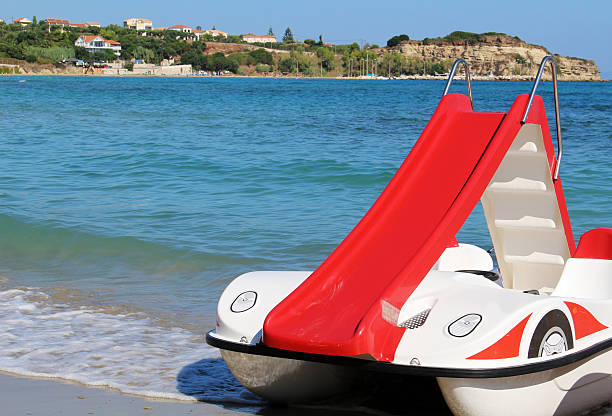 Red pedalo boat with slide on the beach stock photo