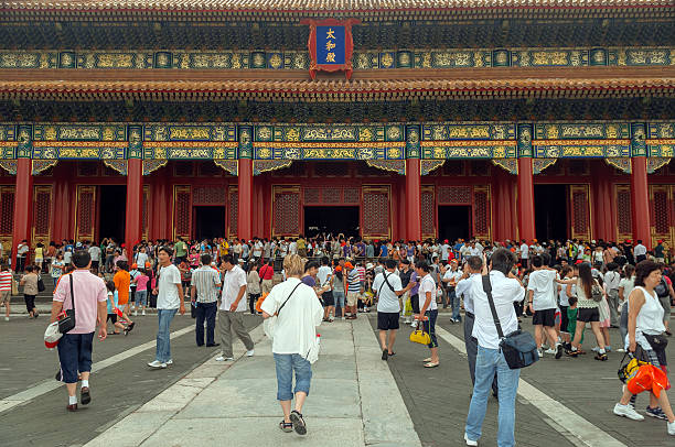 Tourists in Forbidden City after Rain, Beijing, China Lots of Chinese and foreign tourists in Forbidden City after summer rain. Few people still have umbrellas. The stone floor in front is wet and reflects people and buildings. The Forbidden City was the Chinese imperial palace from the Ming Dynasty to the end of the Qing Dynasty. It is located in the middle of Beijing, China, and now houses the Palace Museum. For almost five hundred years, it served as the home of emperors and their households, as well as the ceremonial and political centre of Chinese government. Built in 1406 to 1420, the complex consists of 980 buildings with 8,707 bays of rooms. Nikon D300. Copy space. forbidden city beijing architecture chinese ethnicity stock pictures, royalty-free photos & images