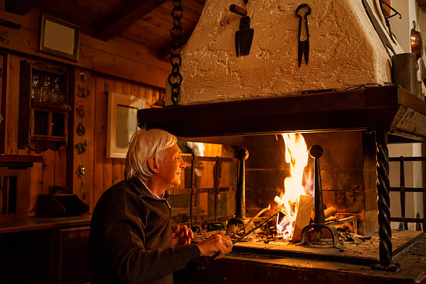 istock White-haired senior man enjoys, makes fire in the fireplace  Chalet 487689636