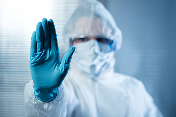 Female scientist in protective hazmat suit with hand raised Scientist with hand raised in hazmat protective suit, stop concept. laboratory photos stock pictures, royalty-free photos & images