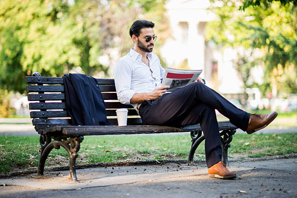 istock Businessman reading newspaper in the park 487691888