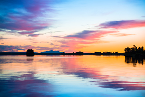 colorful sunset over a calm lake with mountains in the background