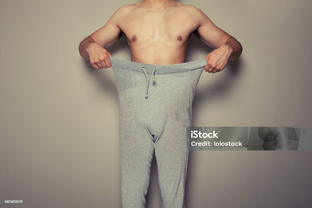 Young man pulling at his trousers A young man is pulling at his trousers Abdomen Stock Photo